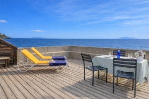 a deck with a table and chairs and the ocean at L'Ortu - maison charmante vue mer - Erbalunga in Erbalunga