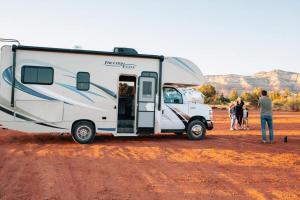 a man standing next to a camper parked in the desert at Milagro Luxury Camps in Merzouga