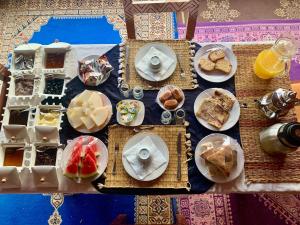 a table topped with plates of food and desserts at Milagro Luxury Camps in Merzouga +39 photos