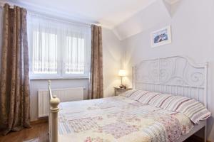 1 dormitorio con cama blanca y ventana en Apartamenty Nadmorskie, en Rewa