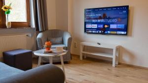 a living room with a couch and a tv on a wall at Hotel Kachelburg in Dieblich