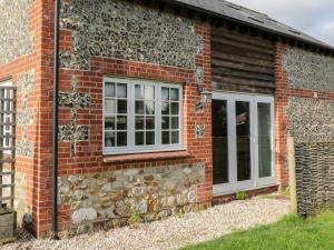 a brick house with two windows and a stone wall at The Barn at Myrtle Cottage in Marlborough