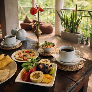 a wooden table with plates of food and cups of coffee at Tantra Ella Lodge in Ella