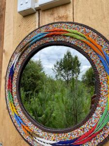 a circular mirror on a wall with a forest at Ndege Cottage in Mai Mahoro