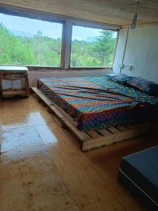a bed in a room with a large window at Ndege Cottage in Mai Mahoro