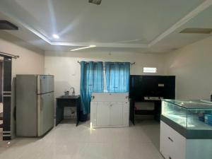 a kitchen with blue curtains and a refrigerator at Hotel Moturi Farmstay Vemulawada in Vemalwāda
