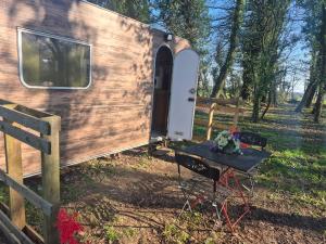 a wooden trailer with a table in front of it at La petite caravane de Vallye in Maxent