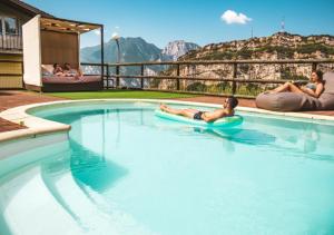 a man laying on a raft in a swimming pool at Hotel Isola Verde in Nago-Torbole