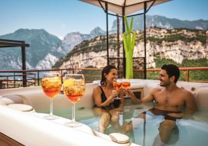 a man and woman sitting in a bath tub with wine glasses at Hotel Isola Verde in Nago-Torbole