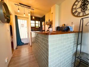 a kitchen with a counter and a clock on the wall at Le Pic'Vert - Escapade Solo ou Duo - Hôpital à 400m - Parking gratuit - GARE & CENTRE HISTORIQUE 15min à pied - Clim - Balcon au calme in Bergerac