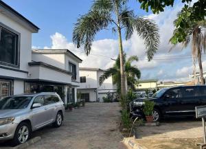 two cars parked outside of a house with palm trees at Studio apartment GRA IKeja in Ikeja