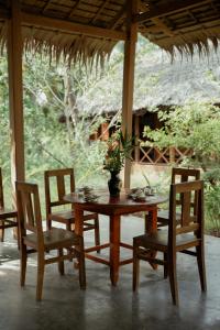 a wooden table and chairs with a potted plant on it at Le Mékong Vert Ecolodge in Ben Tre