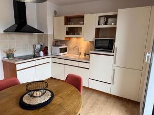 a kitchen with a wooden table and a kitchen with white cabinets at Les Trinitaires in Sarzeau