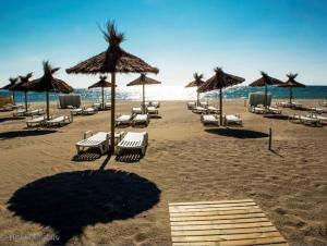 a beach with chairs and umbrellas and the ocean at Maisonnette Les Coraux residence prive avec piscine in Canet-en-Roussillon