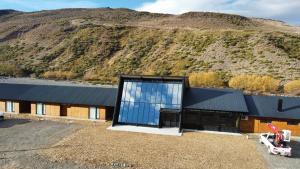 a house with a large window on the side of a mountain at Hosteria Manzano Amargo in Manzano Amargo