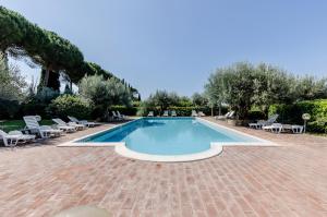 a swimming pool with chairs and a brick patio at GuestHost - Lavanda Apartment with Pool & Parking in Passignano sul Trasimeno +24 photos