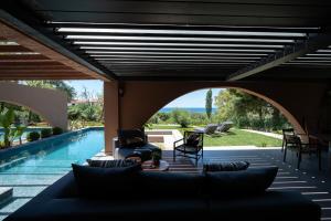 a patio with a couch and chairs and a swimming pool at Euphoria Villa, 9 bdrs with private pools, beachfront in Kalogria