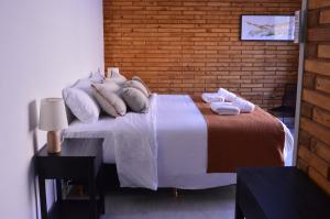 a bedroom with a bed with pillows and a brick wall at Hosteria Manzano Amargo in Manzano Amargo +5 photos