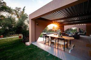 an outdoor patio with a wooden table and chairs at Euphoria Villa, 9 bdrs with private pools, beachfront in Kalogria