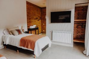 a bedroom with a bed and a brick wall at Hosteria Manzano Amargo in Manzano Amargo