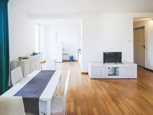 a white living room with a table and a television at Apartment Le Gemme-4 by Interhome in Meina