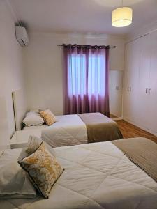 two beds in a hotel room with a window at Santa Maria Goldcrest House in Vila do Porto