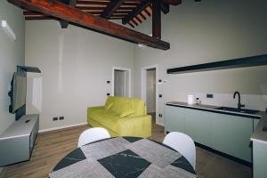 a living room with a yellow chair and a kitchen at Legnago Suite Apartments in Legnago