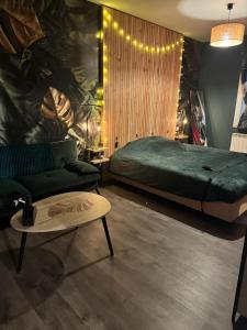 a bedroom with a bed and a couch and a table at Le miroir des désirs in Argentré-du-Plessis