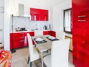 a kitchen with red cabinets and a table and chairs at Apartment Amarena by Interhome in Dormelletto