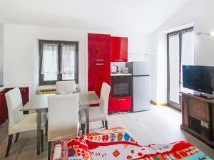 a living room with a table and a kitchen with red cabinets at Apartment Amarena by Interhome in Dormelletto