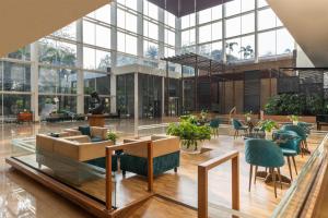 a lobby with chairs and tables and windows at Radisson Blu Plaza Hotel Hyderabad Banjara Hills in Hyderabad