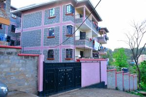 a pink house with a black gate in front of it at Executive 1bedroom Embu by Tsparks in Embu