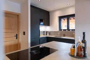 a kitchen with black cabinets and a sink at Alpine Hygge by Villars Luxury in Villars-sur-Ollon