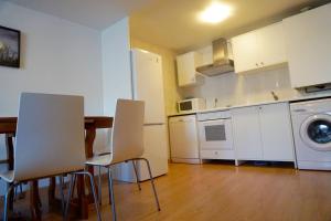 a kitchen with white cabinets and a table and chairs at Apartamentos Turísticos Río Gallego (Apartamento Huesca) in Huesca +9 photos