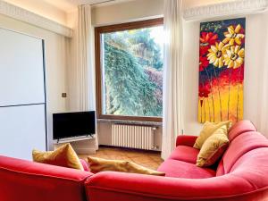 a red couch in a living room with a large window at Apartment Carlui by Interhome in Domaso +22 photos