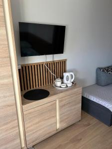 a flat screen tv on a wooden stand with a bed at aleSpanie in Olsztyn