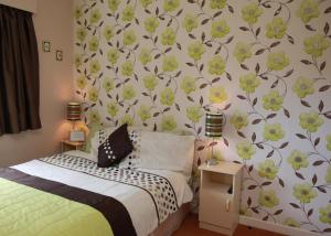 una camera da letto con un letto con fiori verdi e gialli sul muro di Grangeview House B&B a Mullinderg