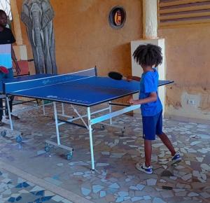 a young boy standing in front of a ping pong table at Ecogîte Dégg-Jàmm in Mbour