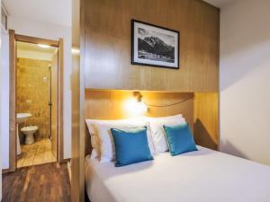 a bedroom with a bed with blue pillows and a bathroom at Apartment Fondue by Interhome in Madesimo