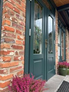 a green door on a brick house with flowers at Cyprianówka in Warszowice