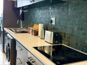 a kitchen with green tiles on the wall at Keddy J Apartments in Windhoek