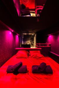 a red bed with two pillows on it with pink lights at Ruby Room in Mâcon