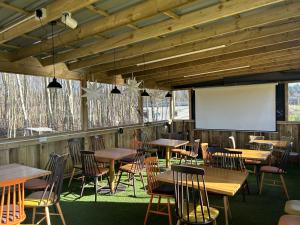 a restaurant with wooden tables and chairs and a screen at North Lodge Glamping in Carnwath