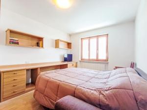 a bedroom with a large bed and a desk at Apartment Casa Dalpi by Interhome in Predazzo