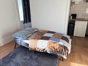 a bedroom with a bed with a quilt on it at Super appartement in Malesherbes