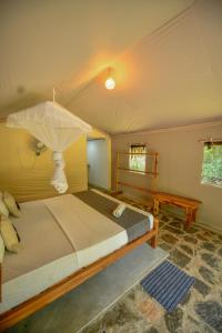 a bedroom with a bed with an umbrella on it at Jungle View River Camping in Udawalawe