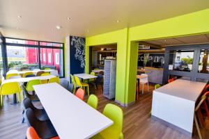 un restaurante con mesas blancas y sillas amarillas en ibis budget Strasbourg La Vigie en Ostwald