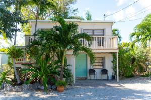 a white house with a balcony and palm trees at Cindy Villa in Key Largo