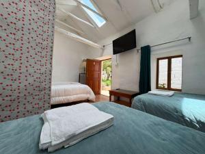 a bedroom with two beds and a television in it at The Green Corner Urubamba in Urubamba