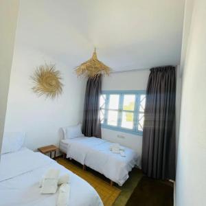 a room with two beds and a window at Appartement Michel Uniquement les familles in Oualidia